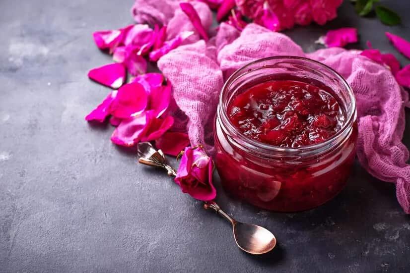 Traditional solar cured gulkand rose preserve in glass jar with fresh roses.